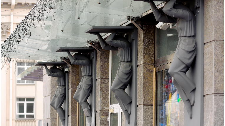 Statues holding up a glass ledge on a building