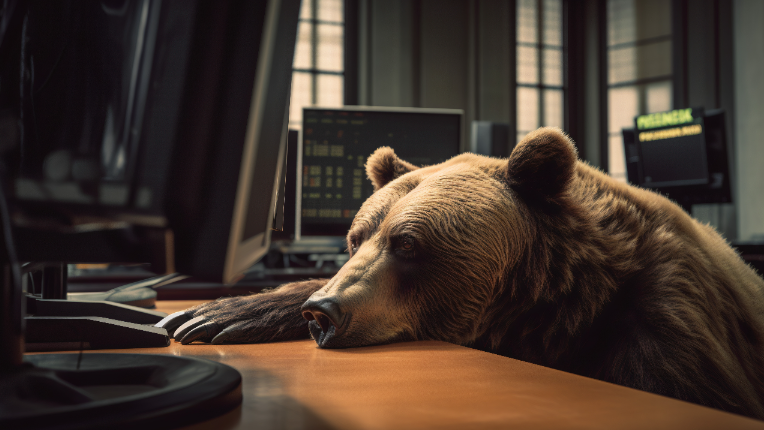 Bear leaning on desk looking at computer.
