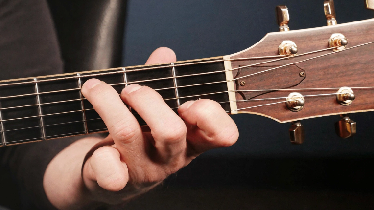 Hand holding fretboard of guitar in C chord formation.